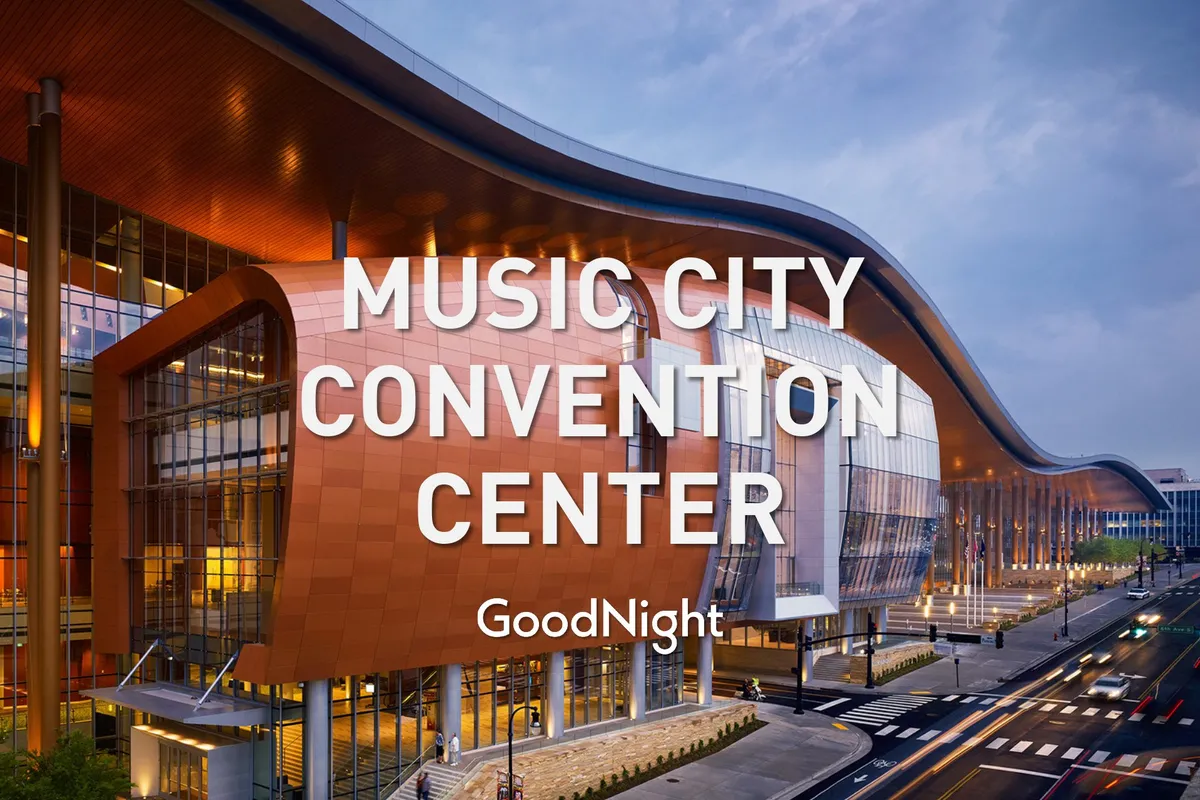 This image captures the dynamic exterior of the Music City Center, with its distinctive curved roof, glass facade, and illuminated signage. The scene radiates a professional, bustling atmosphere typical of major downtown business venues.