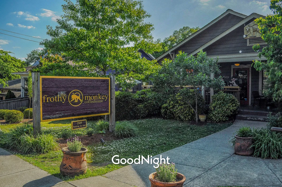 The inviting exterior of Frothy Monkey, a beloved local coffeehouse. The entrance is flanked by greenery, and the scene evokes a welcoming, social vibe, with hints of the neighborhood's vibrant café culture.