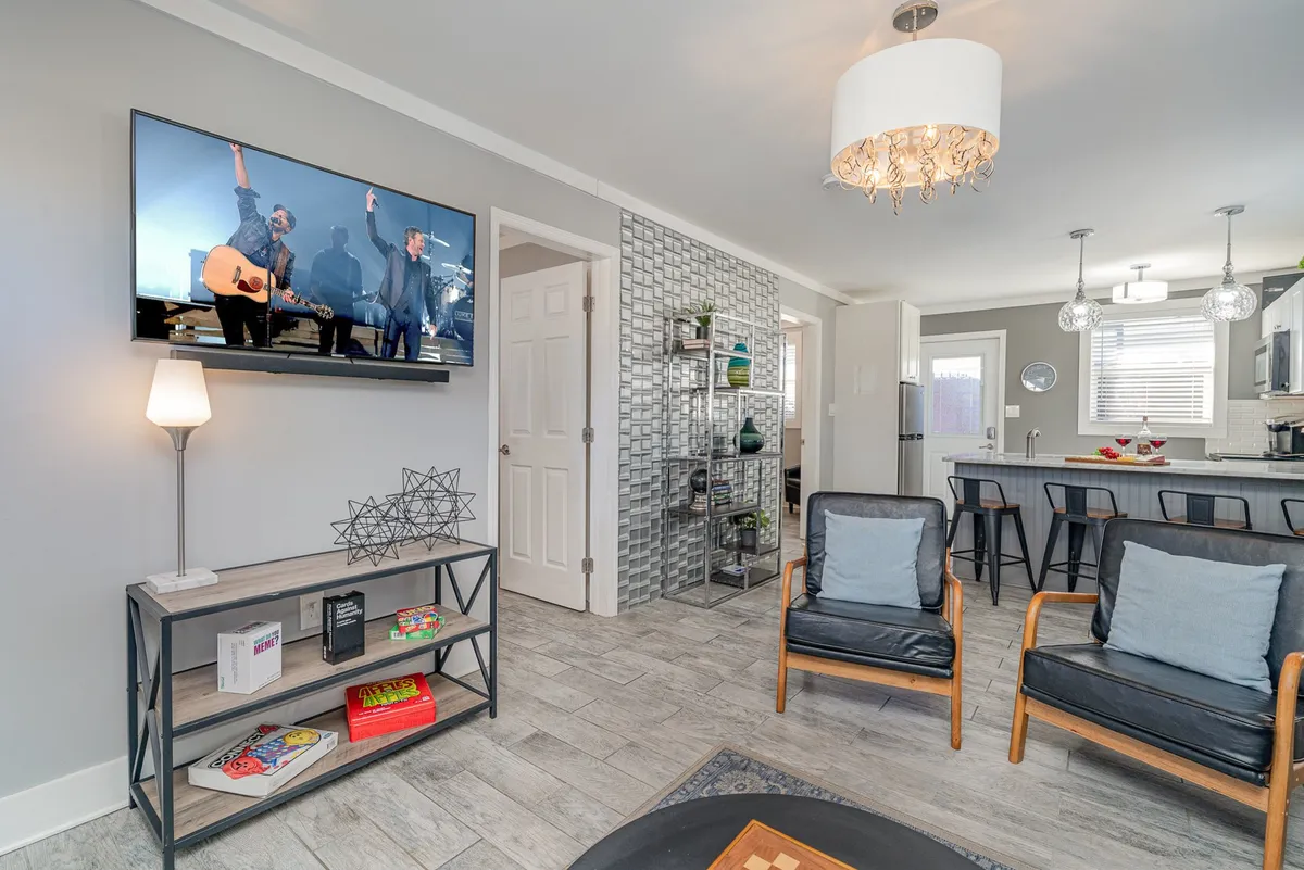 A stylish living room scene with a TV displaying a live performance, contemporary seating, and decorative shelving, creating an inviting environment for group activities or intimate gatherings.
