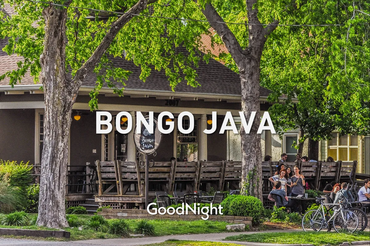 A lively exterior shot of Bongo Java, showing the outdoor seating area shaded by large trees, people enjoying coffee and conversation, and parked bicycles in a welcoming, urban neighborhood setting.