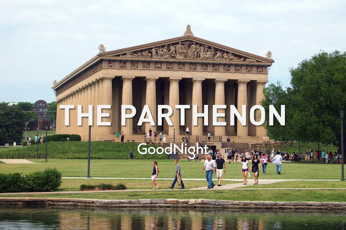 A wide view of The Parthenon replica in Centennial Park, surrounded by lush green grass and people strolling or enjoying outdoor activities. The scene is lively and filled with visitors, set against a bright, open sky.